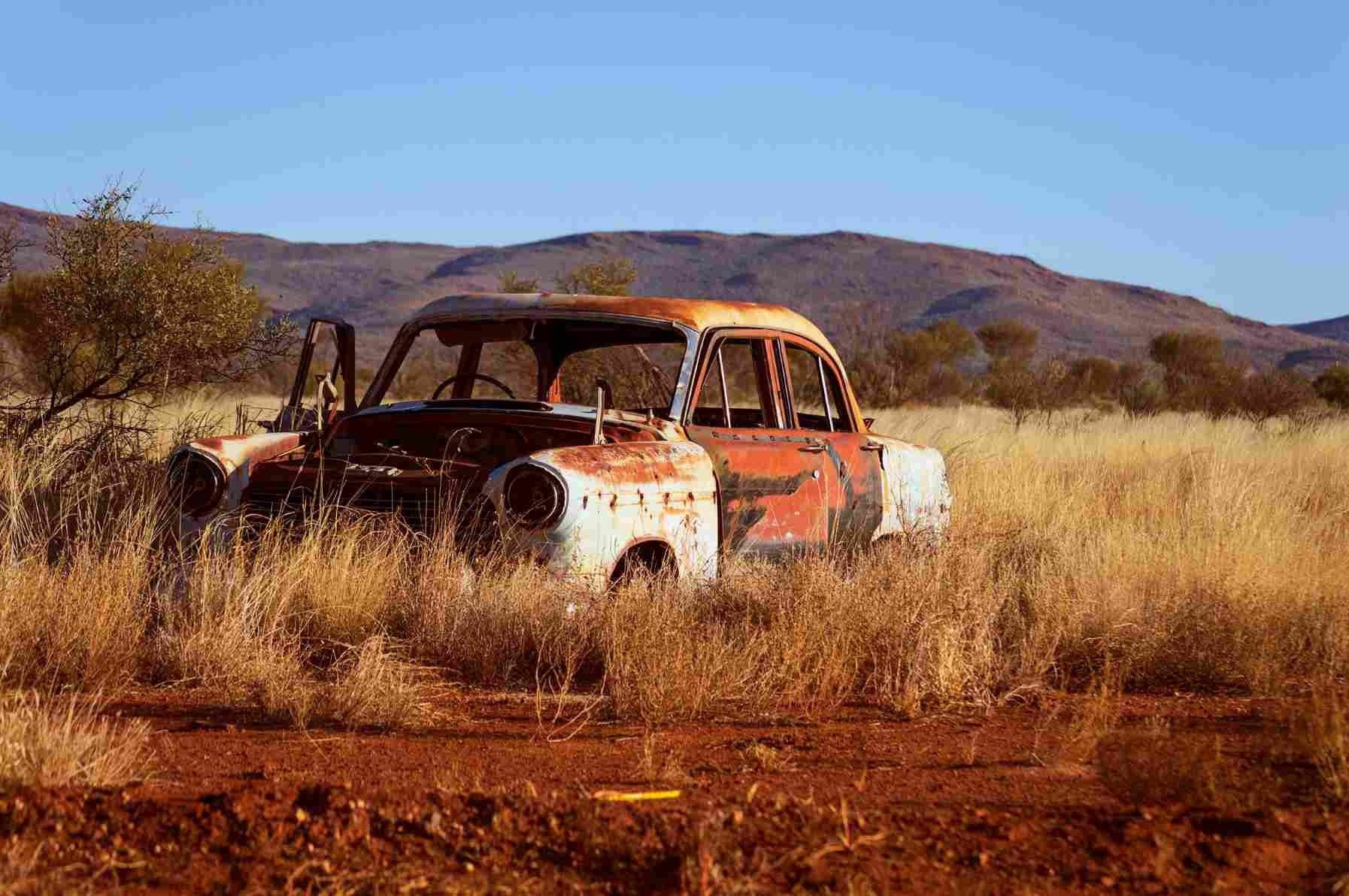 A rusty old car resting in a desert.