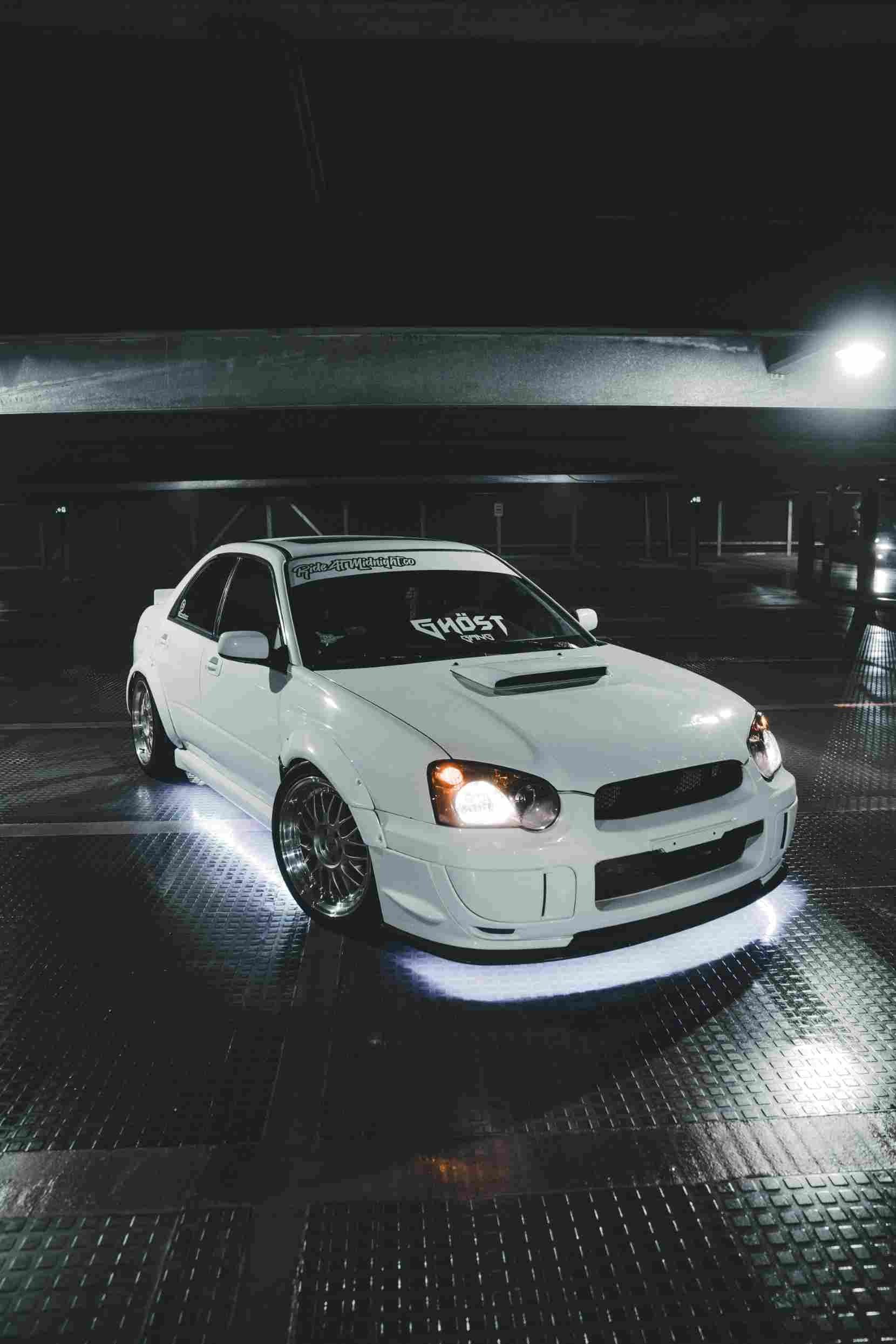 A white sportscar inside a dark garage.