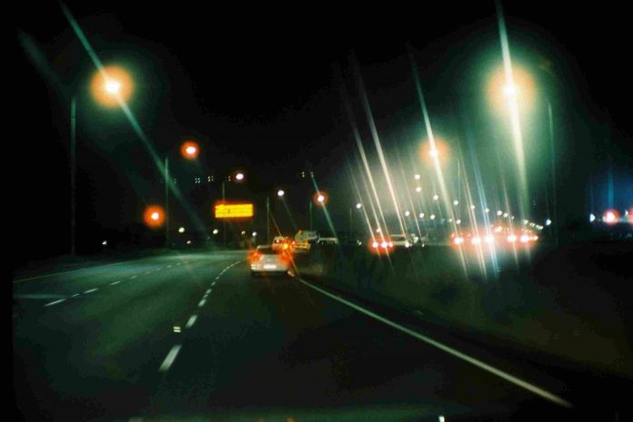 Vehicles driving along a busy interstate highway at night.