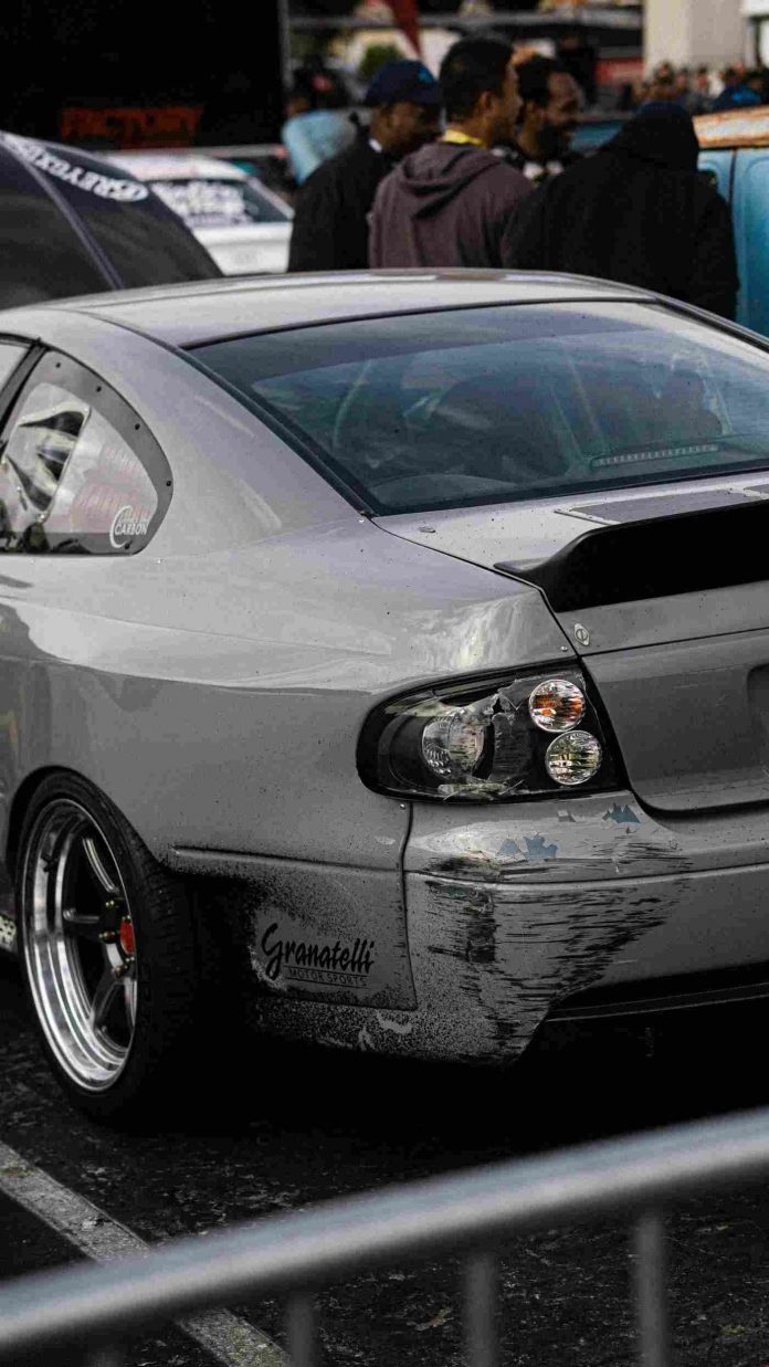 A damaged gray car resting in a parking lot.