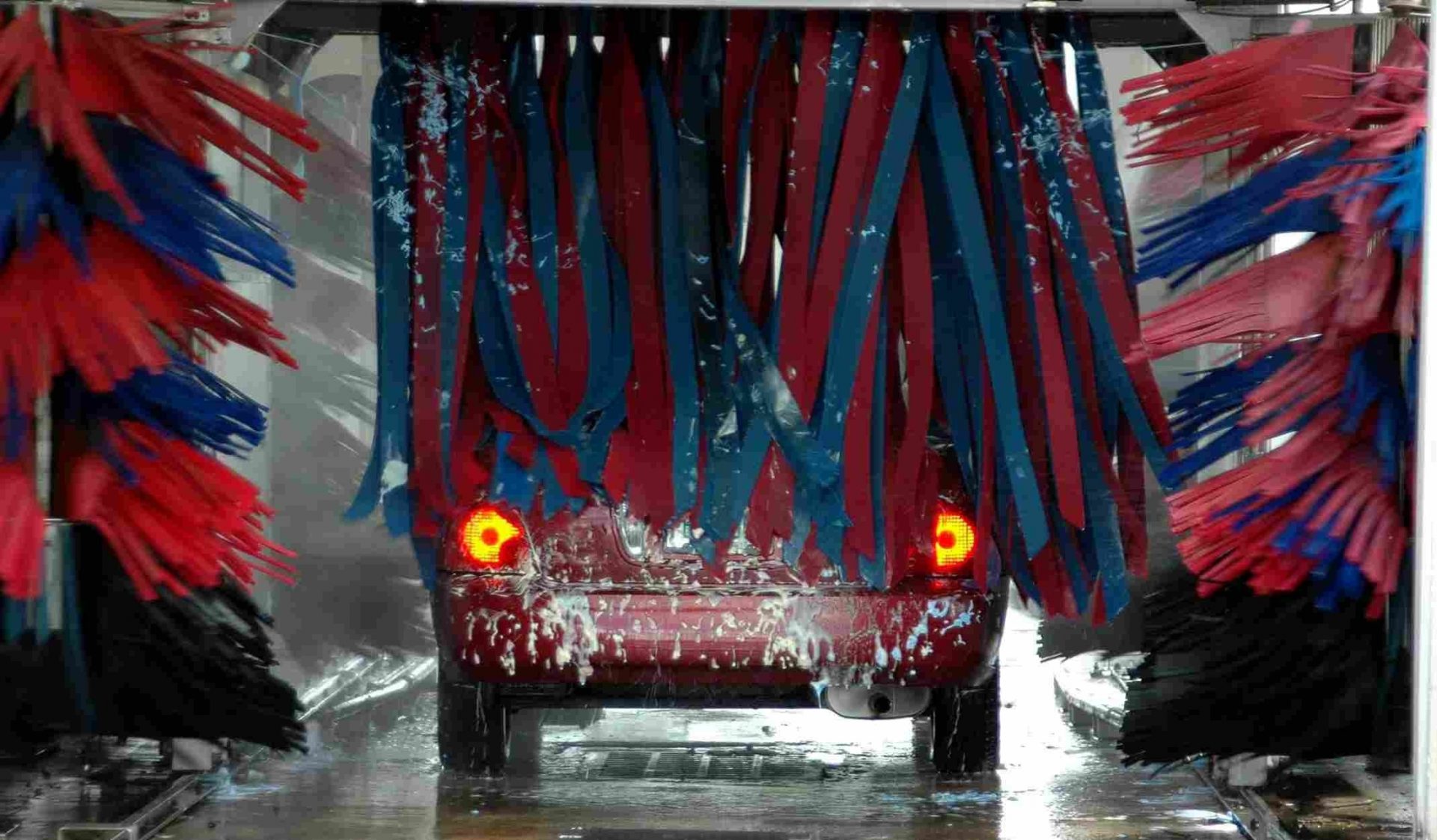 A red car passing through a carwash.