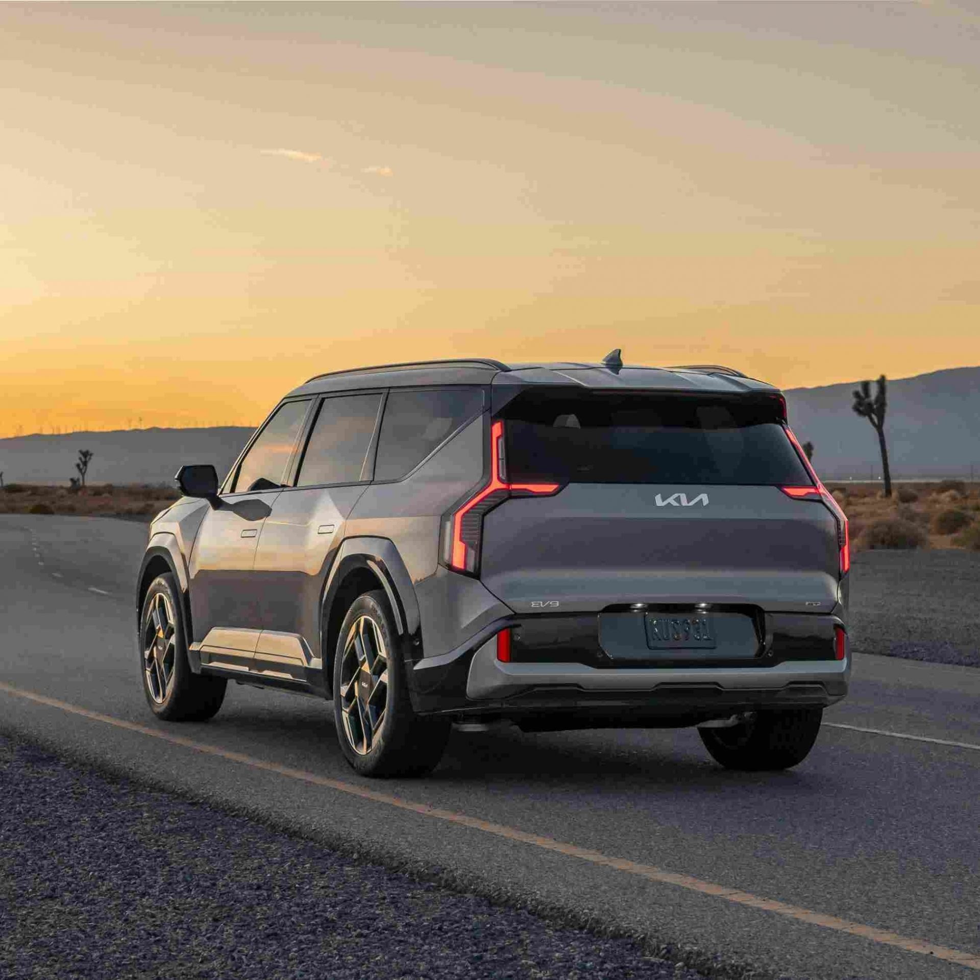 A gray SUV driving along a desert highway at dusk.